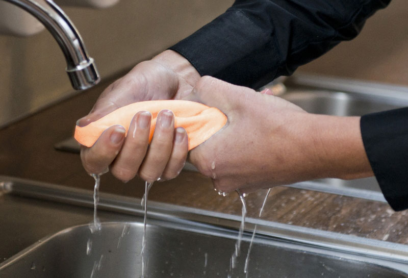 Rinsing microfibre cloth in water.